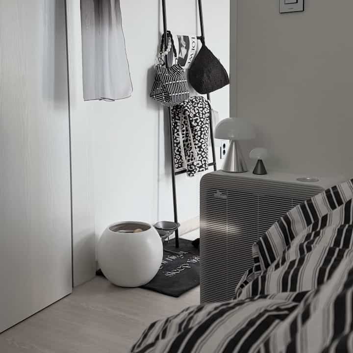 Monotone bedroom space featuring striped bedding and Mina LED mushroom lamps arranged neatly in a minimalistic interior