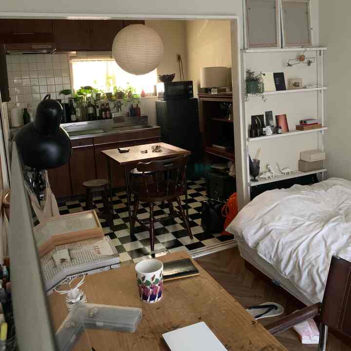ホワイトとブラウンの落ち着いたトーンのワンルーム、ダイニングテーブルやデスク、ベッドが配置された雰囲気のある室内