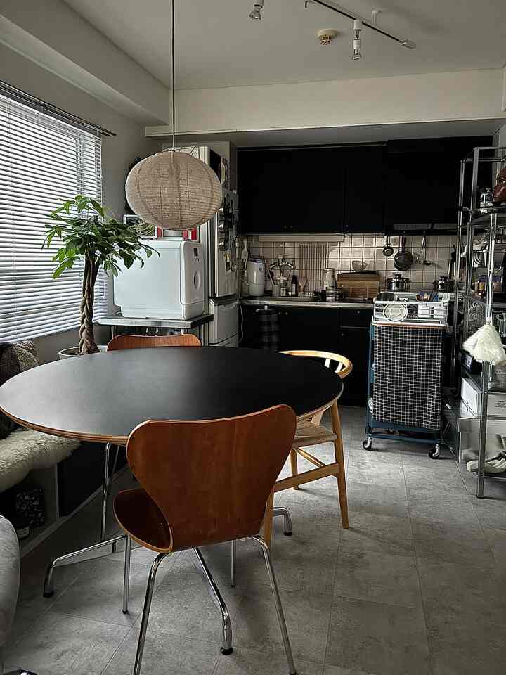 ブラックとブラウンのトーンが調和したコンパクトな一人暮らし向けダイニングルーム、木製ダイニングチェアとペンダントライトが配置されたモダンな空間