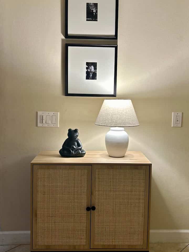 Natural color toned entrance space featuring a wooden sideboard with a table lamp and decor creating a cozy minimalist atmosphere