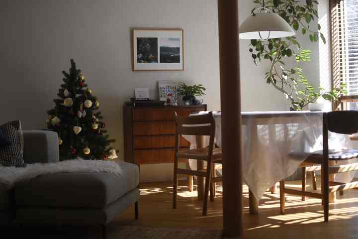 白い壁と木目調家具が配置されたダイニング兼リビング、クリスマスツリーが飾られた雰囲気のあるインテリア