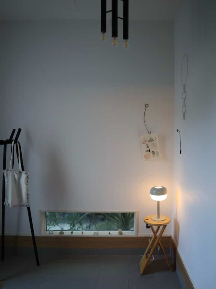 Simple entrance in navy and wood tones featuring a coat rack and table lamp with a calm atmosphere