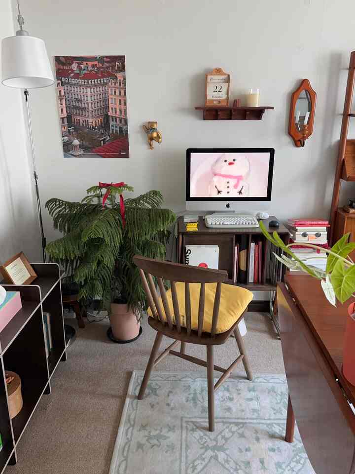 ナチュラルな色調のホームオフィス、机とコンピューター、木製椅子、大きな室内植物が配置された雰囲気のある空間