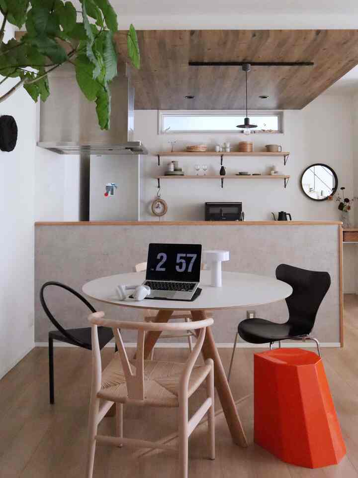 Wood tone and white dining room with a round table and diverse chairs, featuring a modern and minimal atmosphere