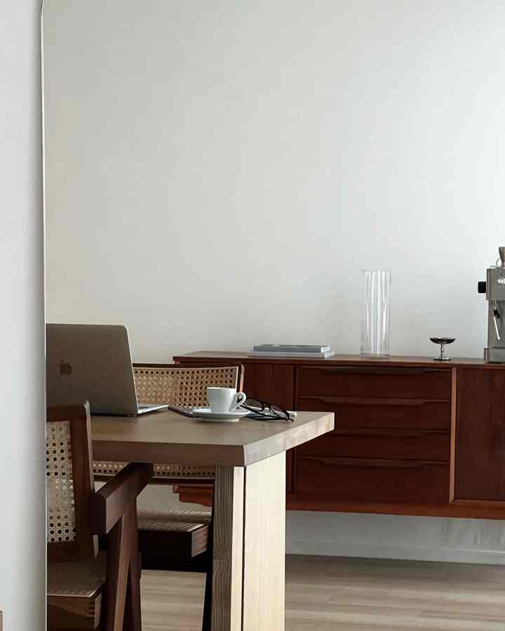 白い壁とブラウンの木製家具が配置された2LDKのリビングルーム、ホームオフィスの雰囲気のあるインテリア