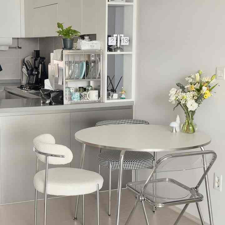 白とモダンな色調のキッチンスペース、ミッドセンチュリーモダンのダイニングテーブルと様々な椅子が配置された印象的なインテリア
