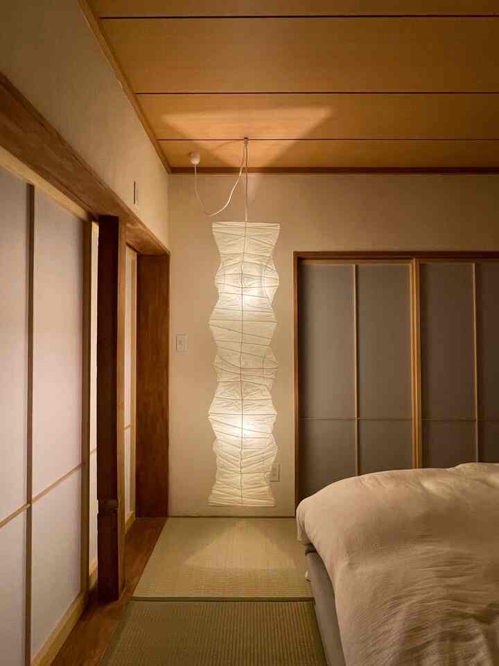 A beige and wood-tone Japanese-style bedroom featuring a central Akari pendant light creating a cozy atmosphere