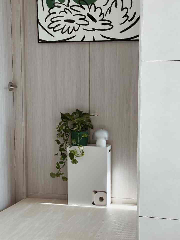 ナチュラルな色調の玄関コーナー、白い収納と植物が配置されたミニマルなインテリア