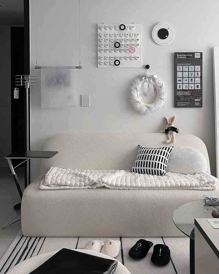 白と黒のモノトーンが映えるリビング、シンプルモダンなソファとラグが配置された清潔感ある空間