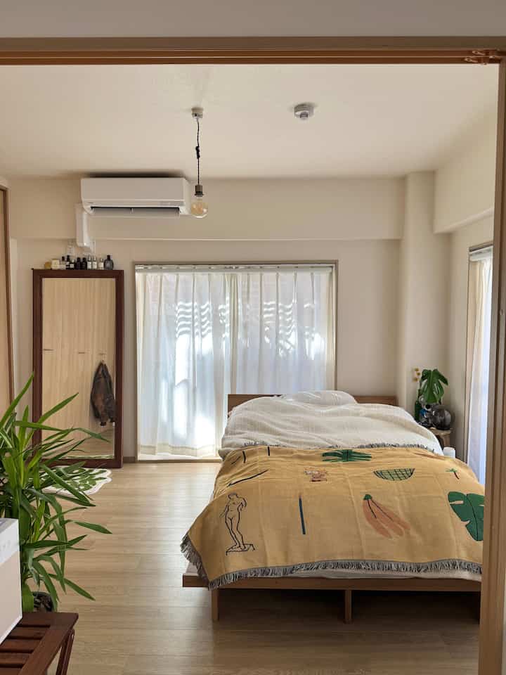 ナチュラルカラーと木目調の寝室、大きな鏡とウッドフレームのベッドが置かれた、落ち着きのある明るい雰囲気のインテリア