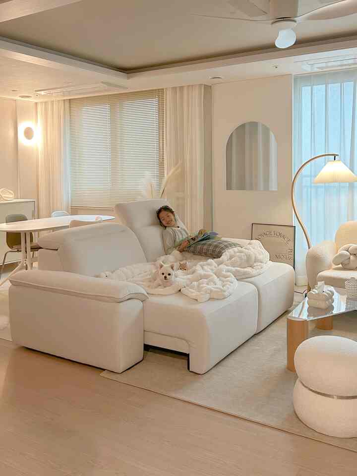 白とナチュラルカラーのリビング、大きなソファにペットと子供がいる落ち着いた雰囲気のあるインテリア