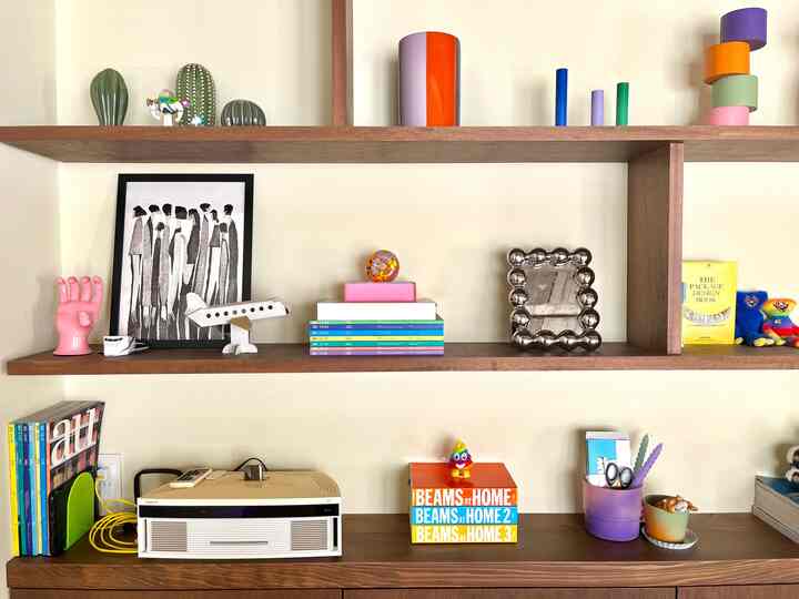 カラフルな装飾品と本が配置されたミッドセンチュリーモダン風のリビングの本棚