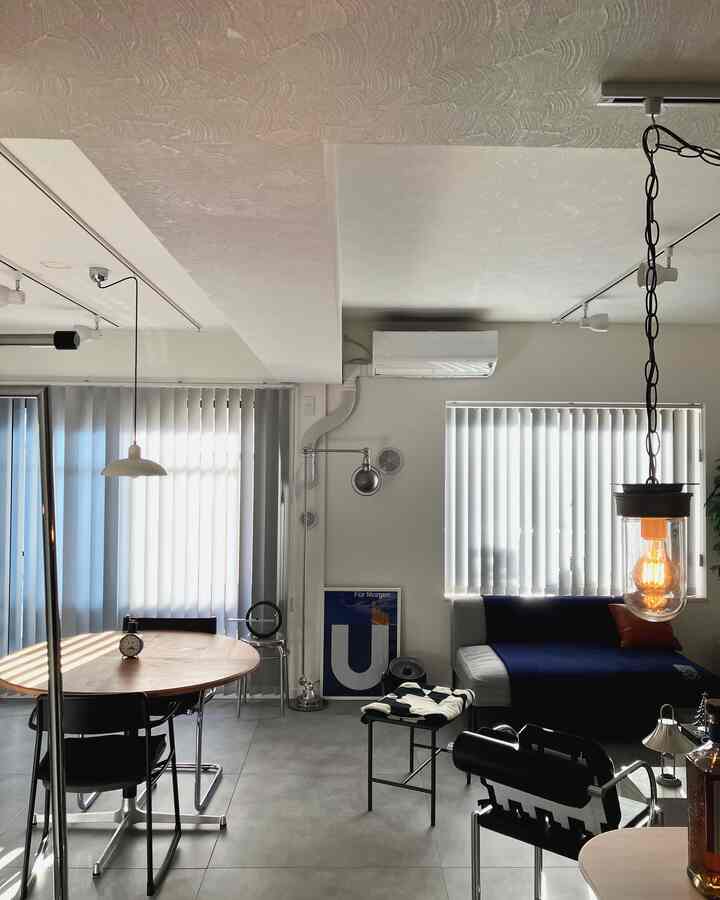 明るいライトグレーの壁と木目調のラウンドダイニングテーブルが配置されたミッドセンチュリーモダンな玄関・リビング空間