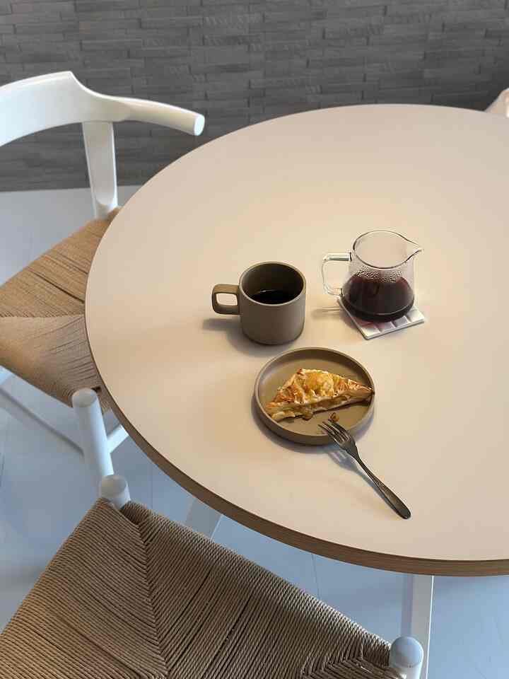白とベージュの色調のダイニングルーム、丸いテーブルにコーヒーとアップルパイが置かれた雰囲気のあるおうちカフェ空間