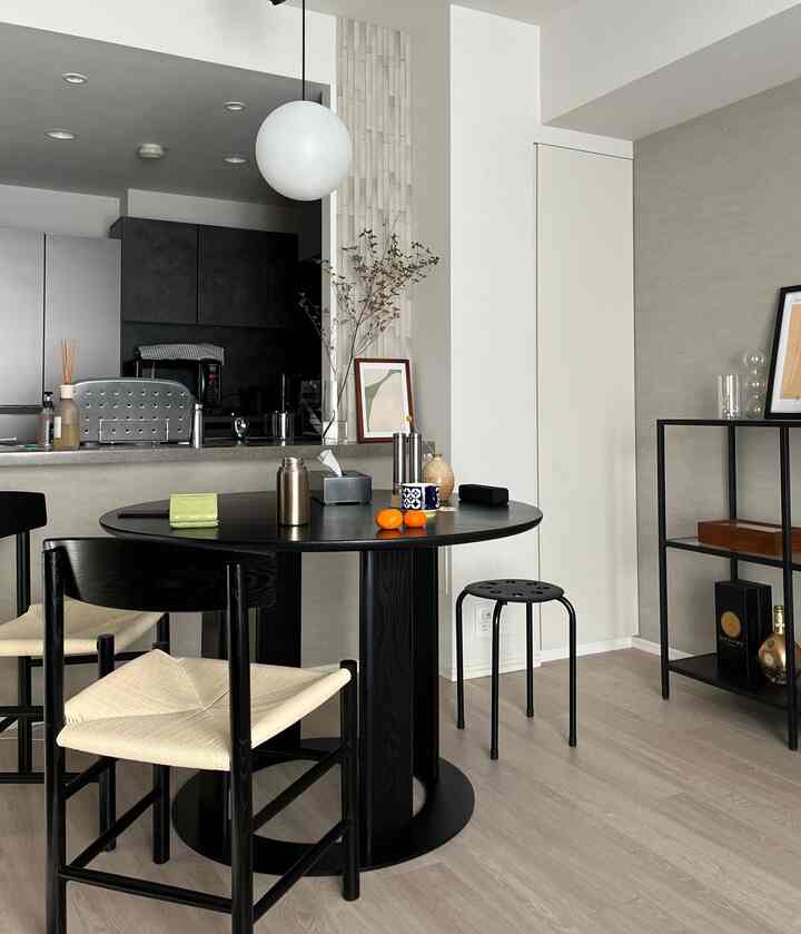 ブラックとアイボリーのトーンのモダンダイニング、丸いダイニングテーブルとキッチンが調和した清潔感のある空間