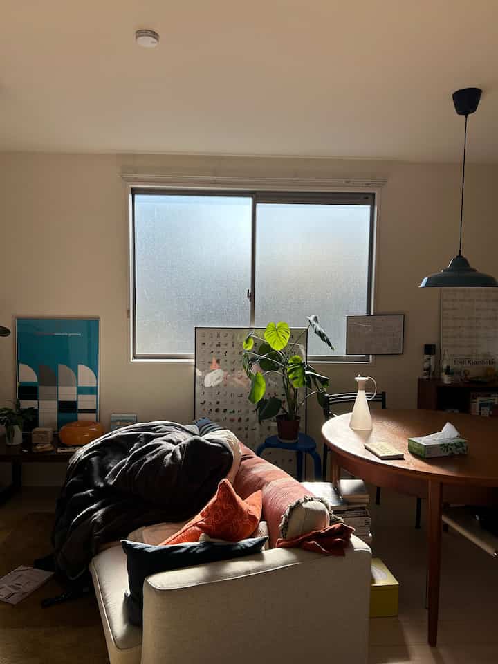 ベージュと木目調が調和するリビング、丸いダイニングテーブルとソファ、植物、ペンダントライトが自然で落ち着いた雰囲気のあるインテリア