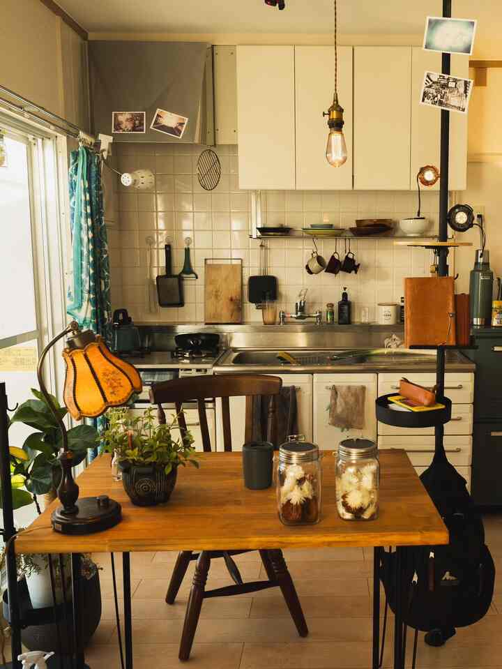 Cozy kitchen space with white tiled walls, brown wooden dining table, and retro lighting elements