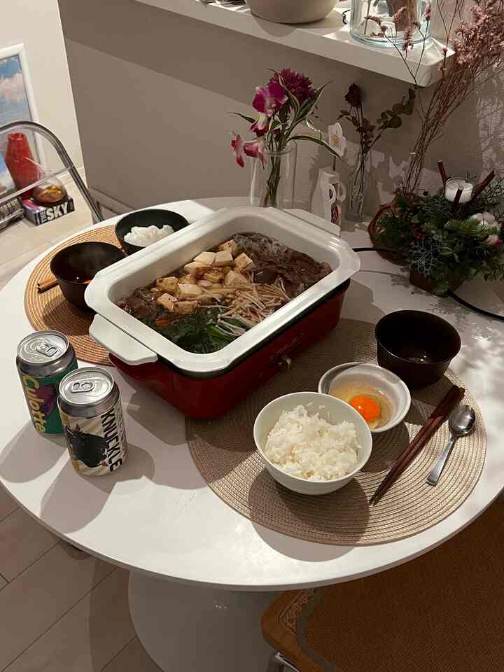 ナチュラルな色調の丸テーブルにすき焼き鍋と食器が並ぶ、一人暮らし向けのシンプルな食事空間