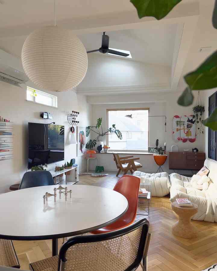 白とナチュラルな色調のリビング、丸いダイニングテーブルと様々な椅子、ラウンジソファが配置された落ち着いたモダンな空間