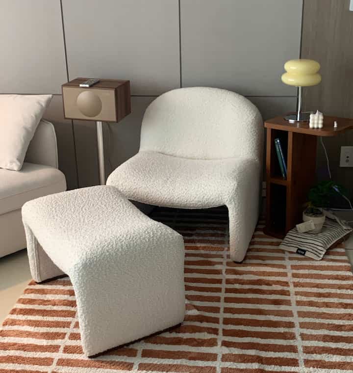 Beige and natural tone living room featuring a bouclé armchair and ottoman, side table creating a cozy atmosphere