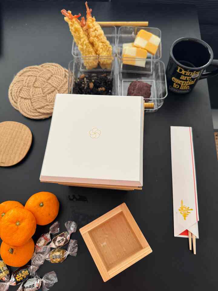 黒いダイニングテーブルの上に透明な仕切りトレイと木製の箱が配置された、自然な雰囲気の食卓空間