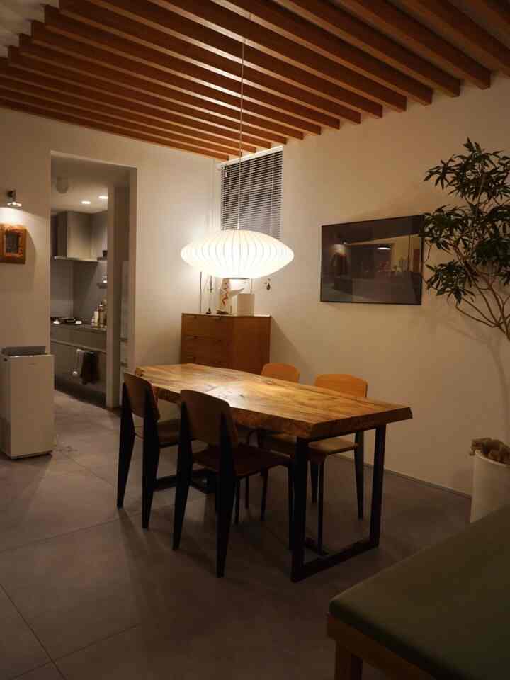 ブラウンの木目調と白い照明が調和したミッドセンチュリーモダンのダイニング、ナチュラルな雰囲気の食卓と椅子が配置された印象的な空間