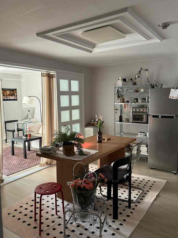 白と茶色のトーンのダイニングルーム、木製のダイニングテーブルと金属製収納棚が配置されたシンプルモダンな空間