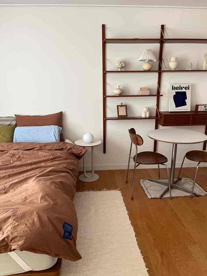 Natural and simple bedroom in soft brown and light brown tones featuring wooden shelves and round table