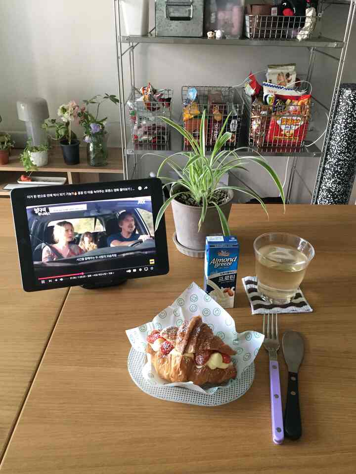 ブラウンの木目調と白が調和したコンパクトなおうちカフェ空間、中央にダイニングテーブルと植物、タブレットが配置された居心地の良いインテリア