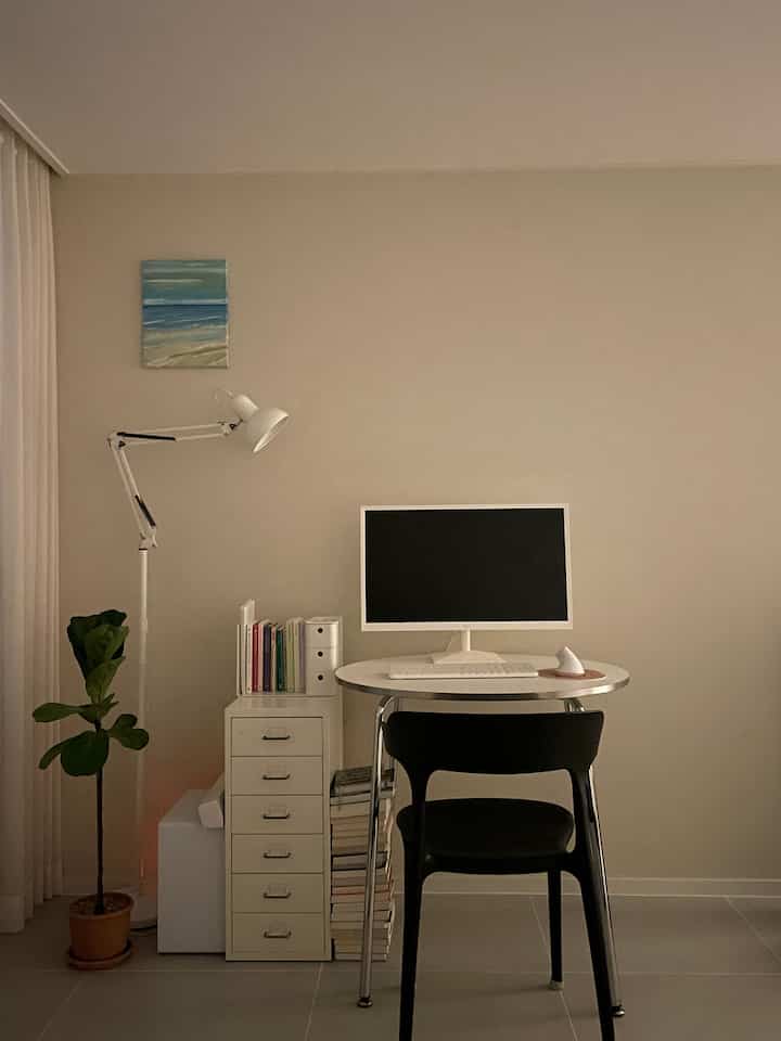 ベージュの壁と白い家具が調和する寝室の一角、小さな書斎スペースでシンプルかつ居心地の良い雰囲気