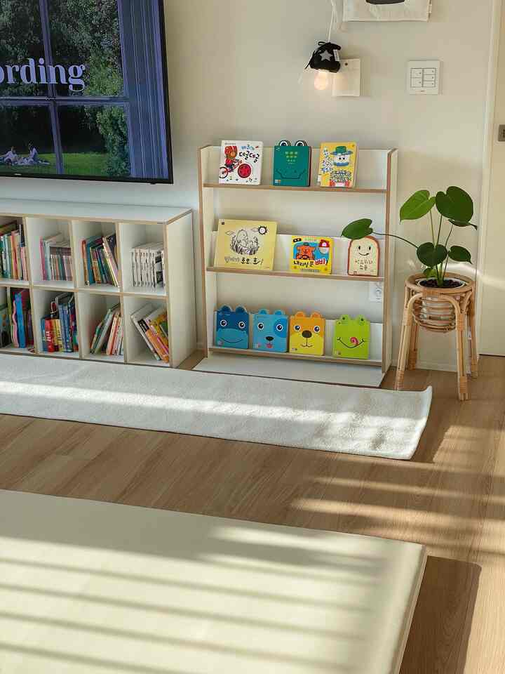 A clean and natural kids' room with white and wood tone theme featuring children's bookshelves and a plant stand