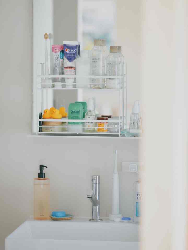 白を基調としたシンプルなバスルームの洗面台、整理された収納棚が配置された清潔感のあるインテリア