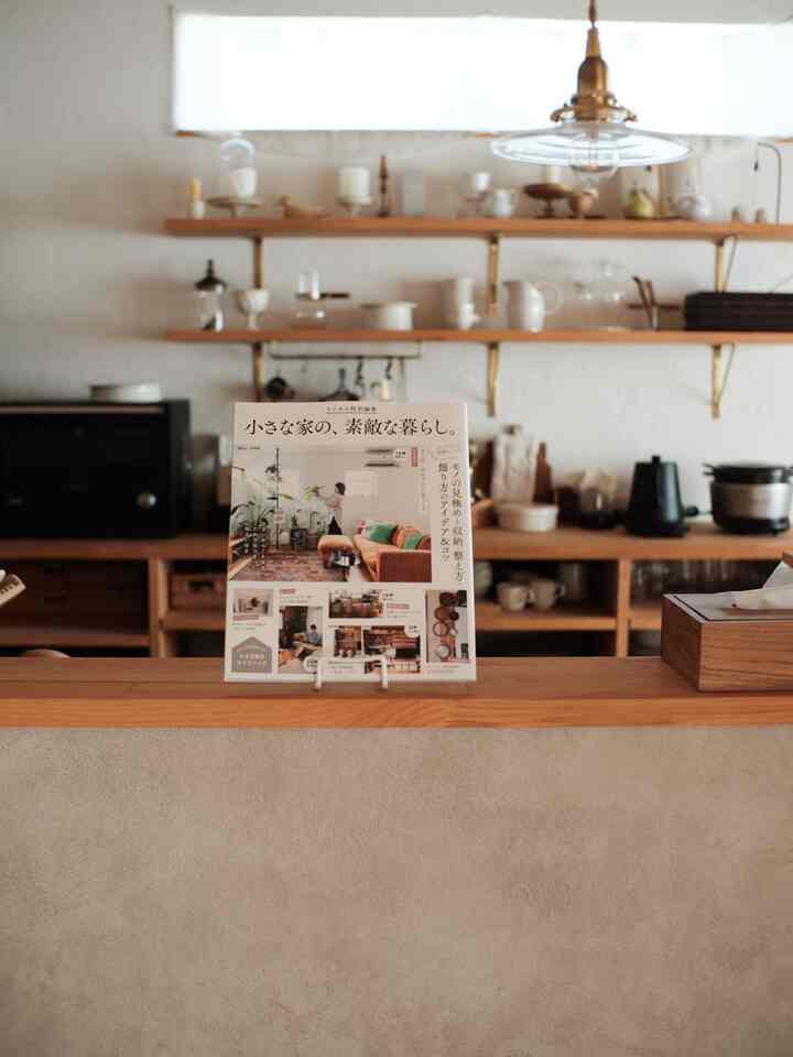 ベージュの壁と木目調のキッチン家具が配置された清潔感のあるキッチン、棚には調理器具とオーブンが置かれている