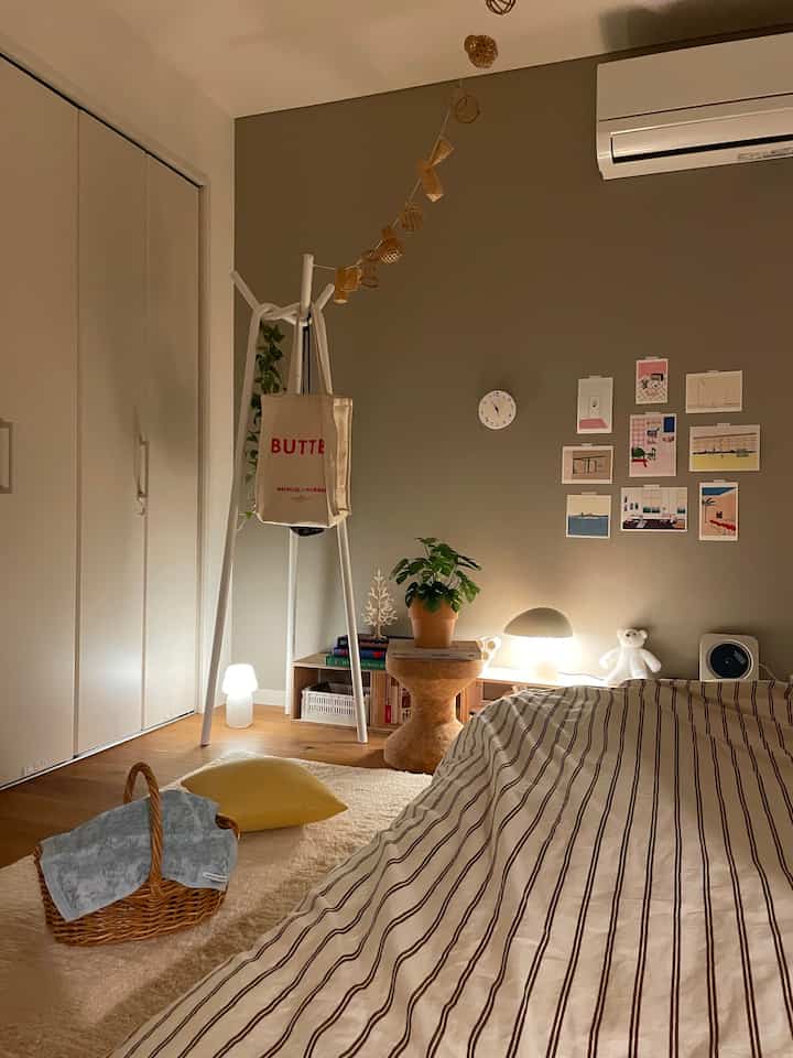 Beige and white toned bedroom featuring MUJI-style stool and coat rack with warm indirect lighting creating cozy ambiance