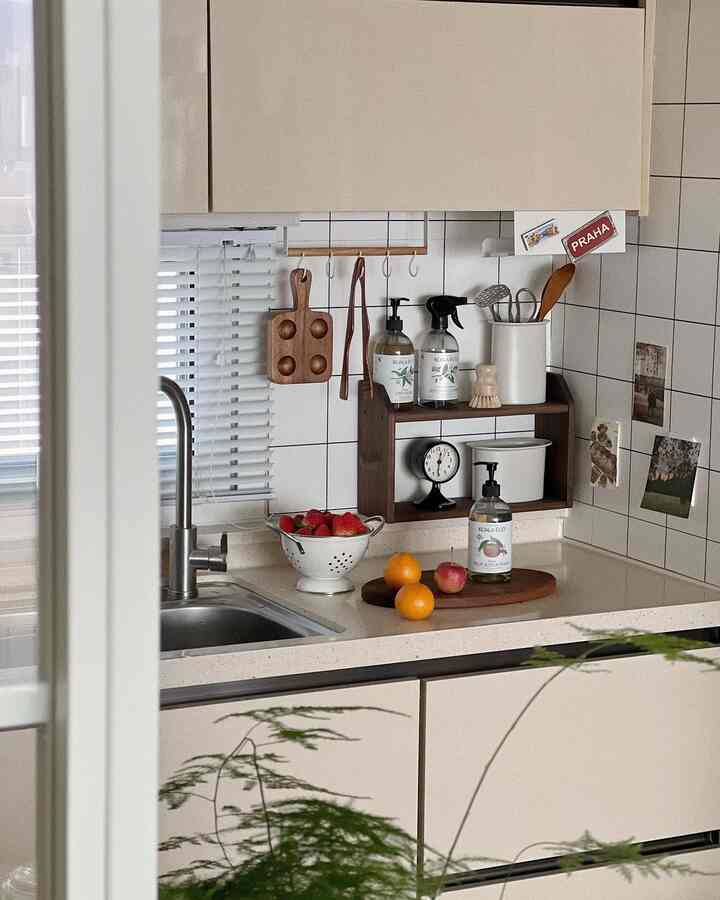 白と茶色のトーンのキッチン、白いタイル壁と木製の小物が調和する清潔感のある調理空間