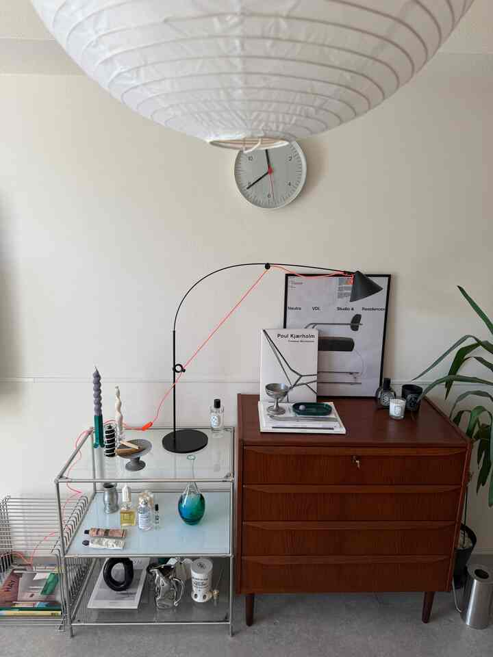 White-walled space featuring a mid-century modern dresser, a table lamp with orange cord, and an indoor plant creating a clean setting