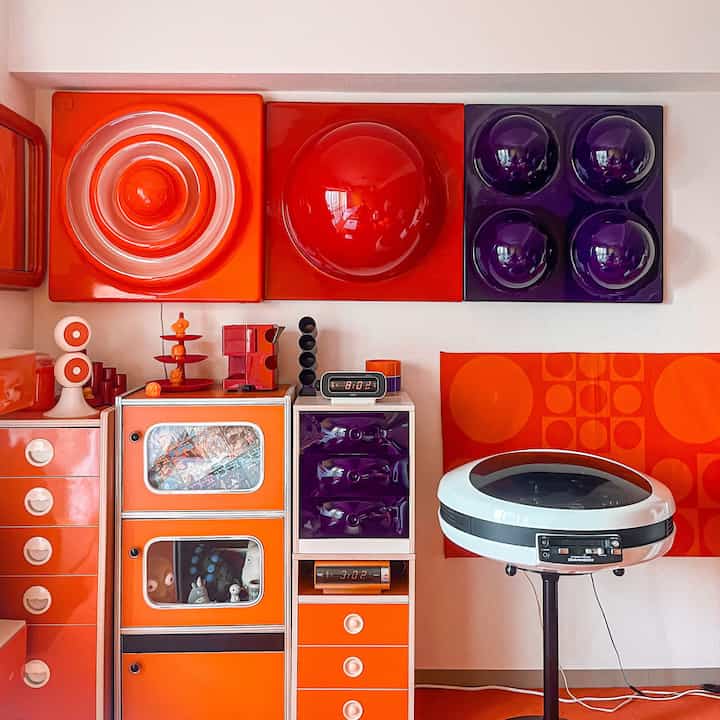オレンジと紫を基調としたレトロインテリア、壁照明とユニークな家具が配置された昭和レトロスタイルの空間