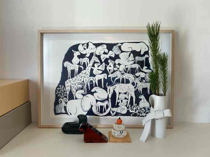 ナチュラルカラーの玄関に動物モチーフのポスター、透明なガラスの鳥のオブジェと緑の植物が配置された落ち着いたインテリア