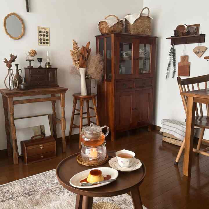 Cozy living room with warm wood tones and vintage furniture, featuring a coffee table set with tea and pudding