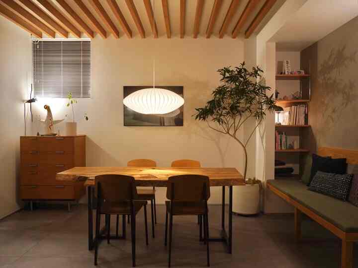 ナチュラルな色調のダイニング、木製のテーブルと観葉植物が配された雰囲気のあるインテリア