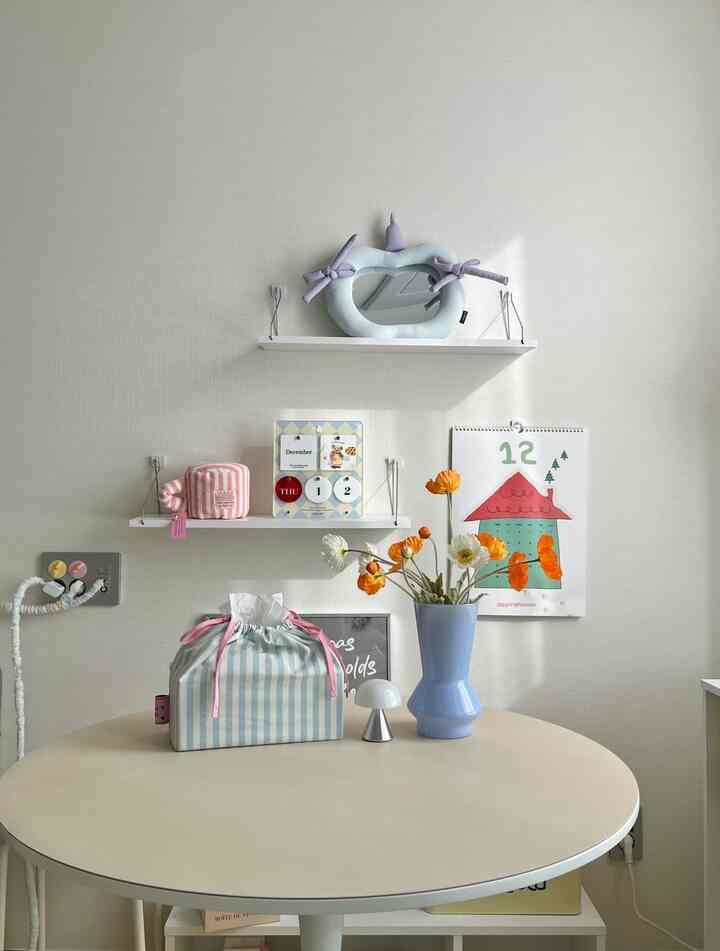 明るいホワイトとベージュの色調のダイニング、丸テーブルの上にパステルカラーの花瓶と装飾品が配置された雰囲気のあるインテリア