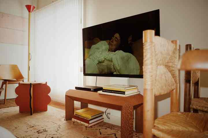 ホワイトとブラウンの色調のリビング、ミッドサイズのテレビと木製家具が配置されたヴィンテージミッドセンチュリーモダンな雰囲気のあるインテリア