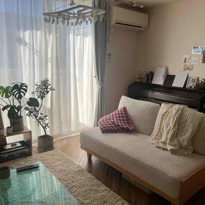 Natural-toned living room filled with bright sunlight, featuring a cream sofa and white curtains creating a warm atmosphere