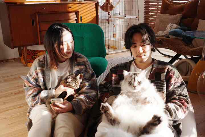 ナチュラルカラーのリビング、二人が猫を抱く穏やかな雰囲気のあるインテリア