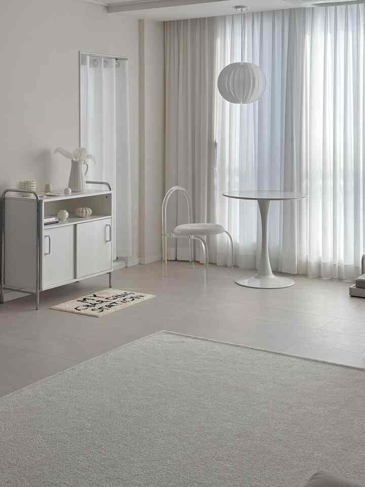 Minimal white and transparent living room featuring a round dining table and acrylic chair in a clean space