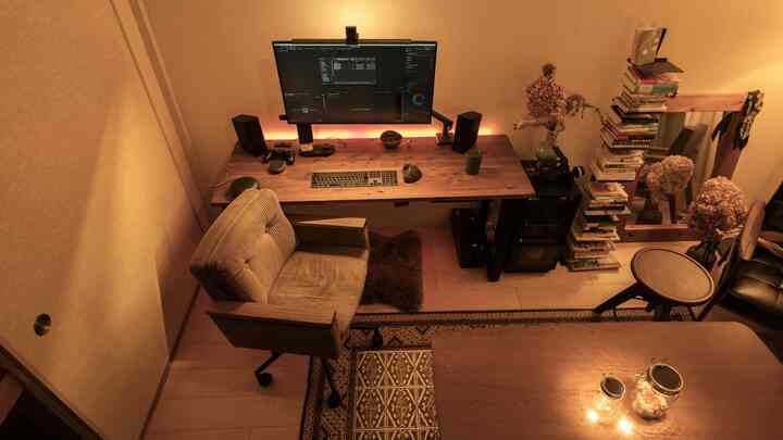 ブラウンとベージュの色調のコンパクトなホームオフィス、木製のデスクとオフィスチェア、本棚とリビングスペースが調和した雰囲気のあるインテリア