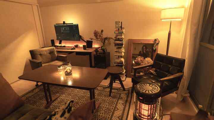 Cozy home office with warm lighting and wood furniture, featuring desk setup and comfortable seating