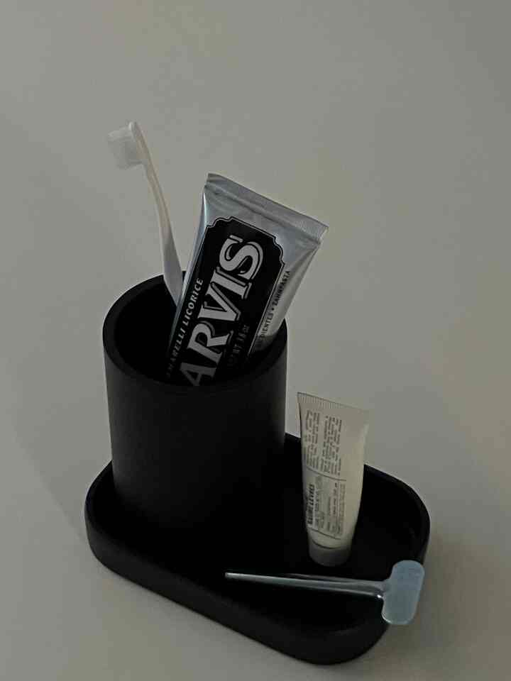 Simple bathroom setup featuring a black toothbrush holder with toothpaste and toothbrush