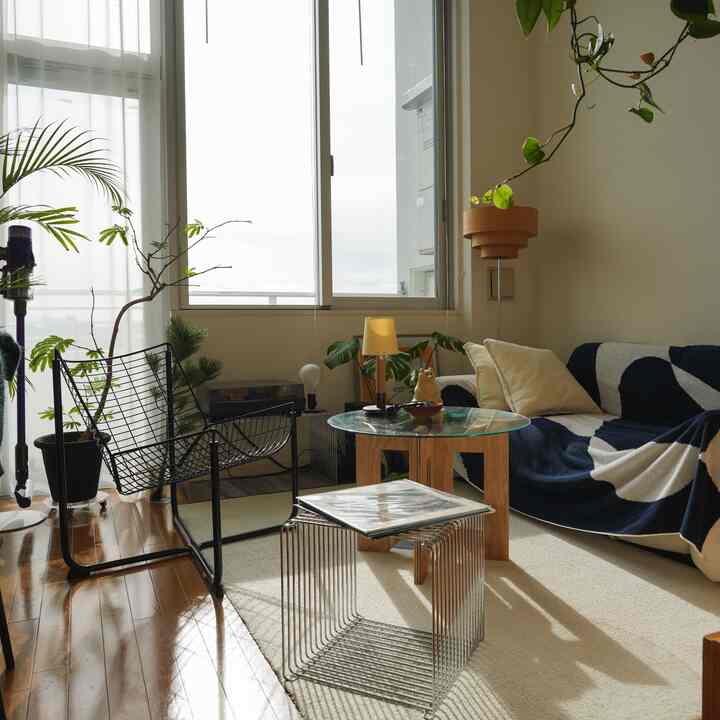 白と茶色の色調のリビング、ネイビーのソファと窓辺にレコードプレーヤーが配置された雰囲気のあるインテリア