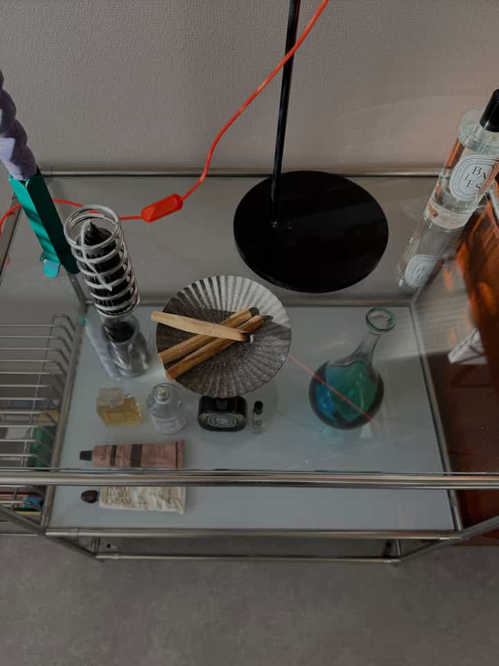 Transparent glass modular shelf featuring black candle, palo santo sticks, and fragrance items arranged neatly